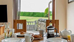A breakfast setup with croissants, coffee, and juice, overlooking a garden.