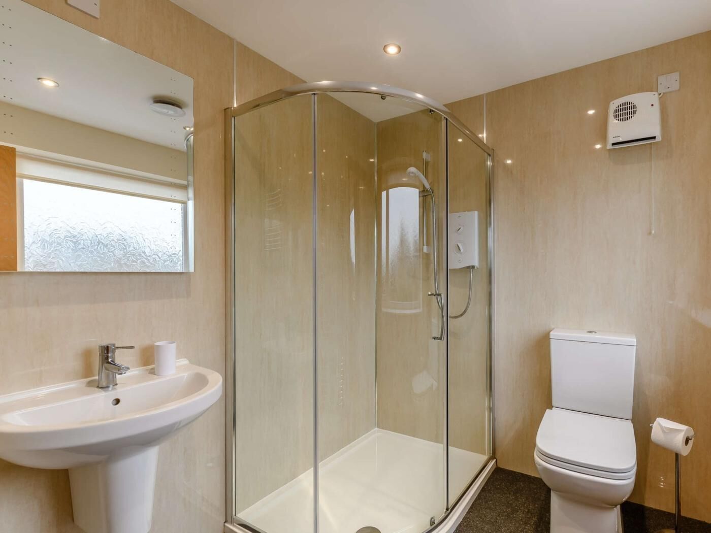 A modern bathroom with a glass-enclosed shower, a white sink, and a toilet.
