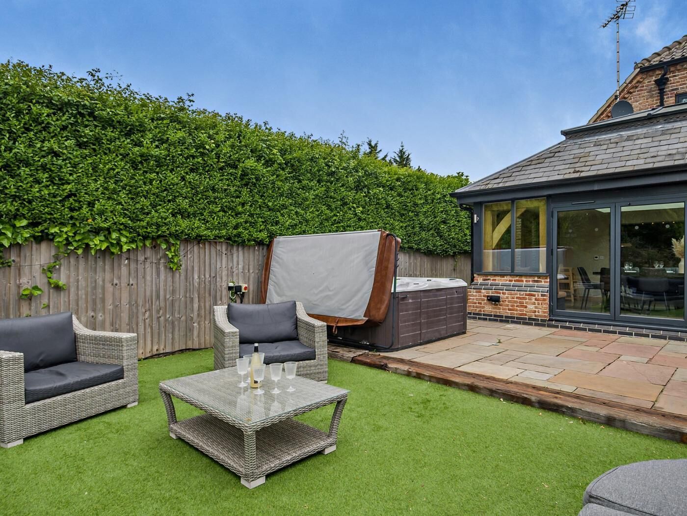 A patio with outdoor furniture, a hot tub, and a covered seating area.