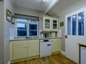 Eine Küche mit Geschirrspüler, einem Fenster mit Jalousien und einer Tür mit Fenster.