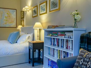 Quarto bem organizado com cama, mesas de cabeceira, uma estante de livros e um mapa na parede.