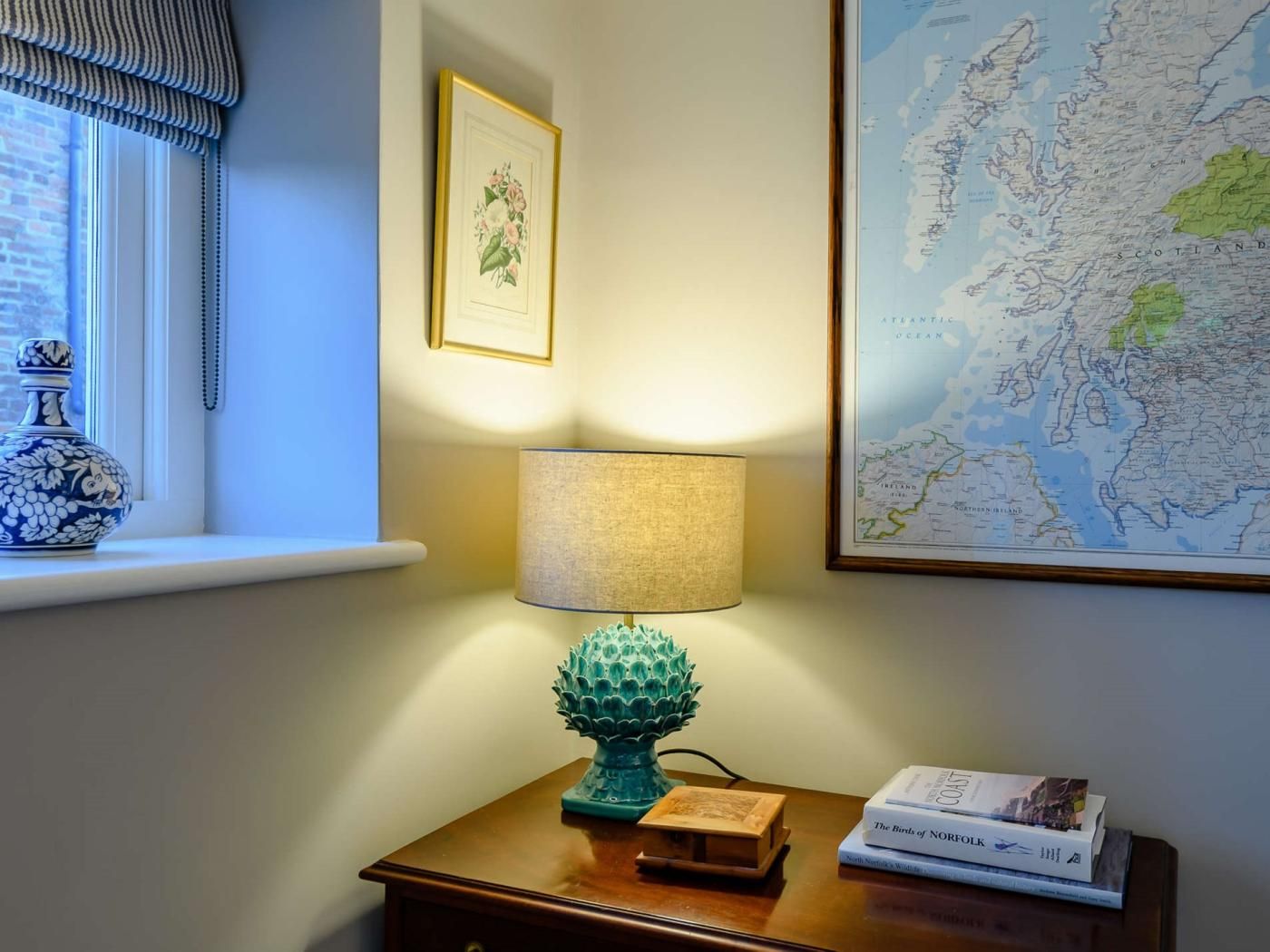 Ein Zimmer mit einer Karte an der Wand, einer Lampe auf einem Beistelltisch und einer dekorativen Vase.
