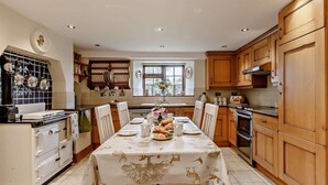 Una cocina con armarios de madera, una mesa de comedor preparada para cuatro personas y un ventanal con vistas.