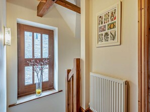 A staircase with a wooden handrail, a window with a view of the outside, and a framed botanical illustration on the wall. - 2 Bed in Brecon (oc-91085) (Llangorse)