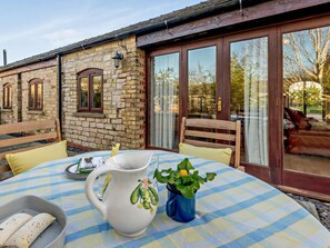 A stone building with large windows, a table with a checkered tablecloth, a pitcher, and a blue mug with a plant. - 2 Bed in Lincoln (oc-91059) (Ashby de la Launde)