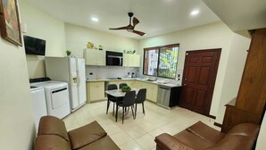 A compact kitchen with a dining area, a ceiling fan, and a brown leather sofa. - Apto nuevo - Comunidad segura cerca de SJO y SJ (Heredia)