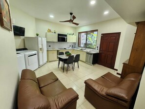 Eine kleine Küche mit Essbereich, Deckenventilator und braunem Ledersofa.