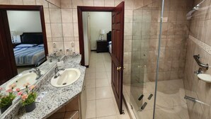 A bathroom with a shower, two sinks, a mirror, and a skylight. - Apto nuevo - Comunidad segura cerca de SJO y SJ (Heredia)