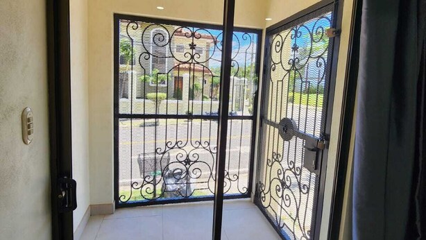 A room with a sliding glass door leading to an outdoor balcony with a metal gate. - Apto nuevo - Comunidad segura cerca de SJO y SJ (Heredia)