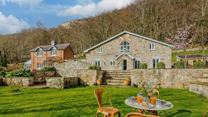 A stone house with a stone wall and a grassy lawn in front. - 6 Bed in Abergele (oc-91054) (Llanddulas)