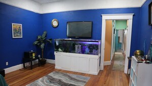 Ein Wohnzimmer mit Aquarium, Flachbildfernseher und Pflanze.