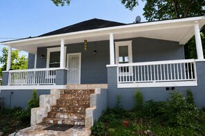 A two-story house with a porch, stone steps, and a satellite dish. - The Brown Mill Residence. (Atlanta)