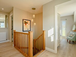 A modern interior with a wooden staircase, a framed abstract artwork, and a light-colored floor. - 2 Bed in Shaftesbury (oc-91172) (Motcombe)