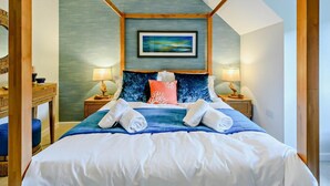 Ein Schlafzimmer mit einem Bett, zwei Nachttischlampen, einem gerahmten Bild an der Wand und einem Holz-Kopfstück.