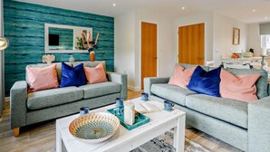 Ein Wohnzimmer mit zwei grauen Sofas, einem weißen Couchtisch und teal-farbenen Wänden.