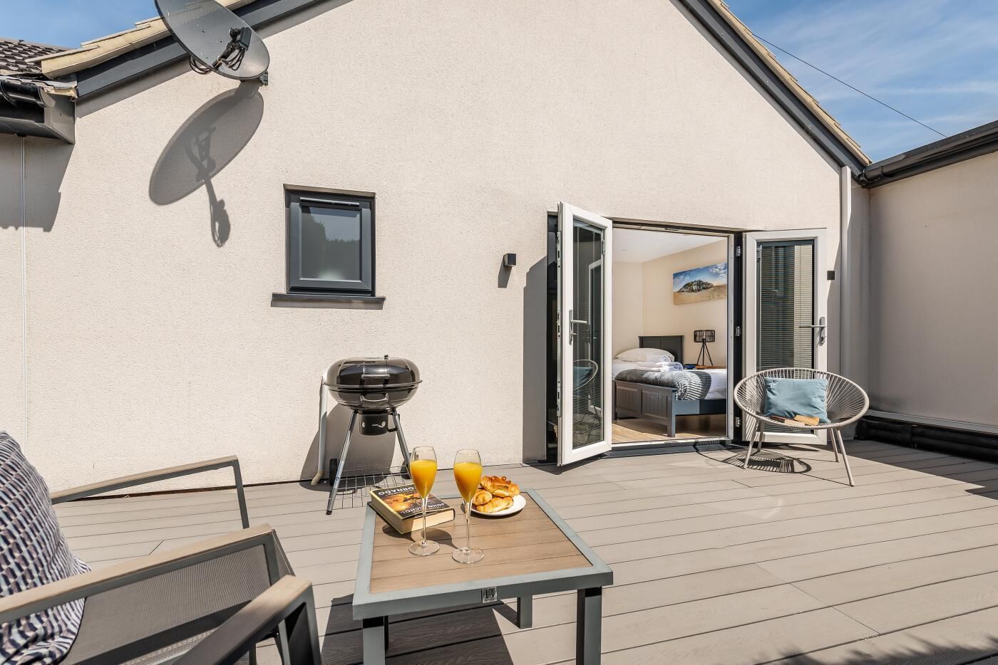 A balcony with a table set for breakfast, a grill, and a chair.