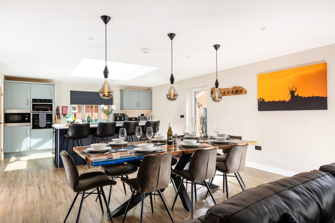 Una cocina moderna con electrodomésticos integrados, un comedor con mesa y sillas de madera, y un amplio ventanal que proporciona luz natural.