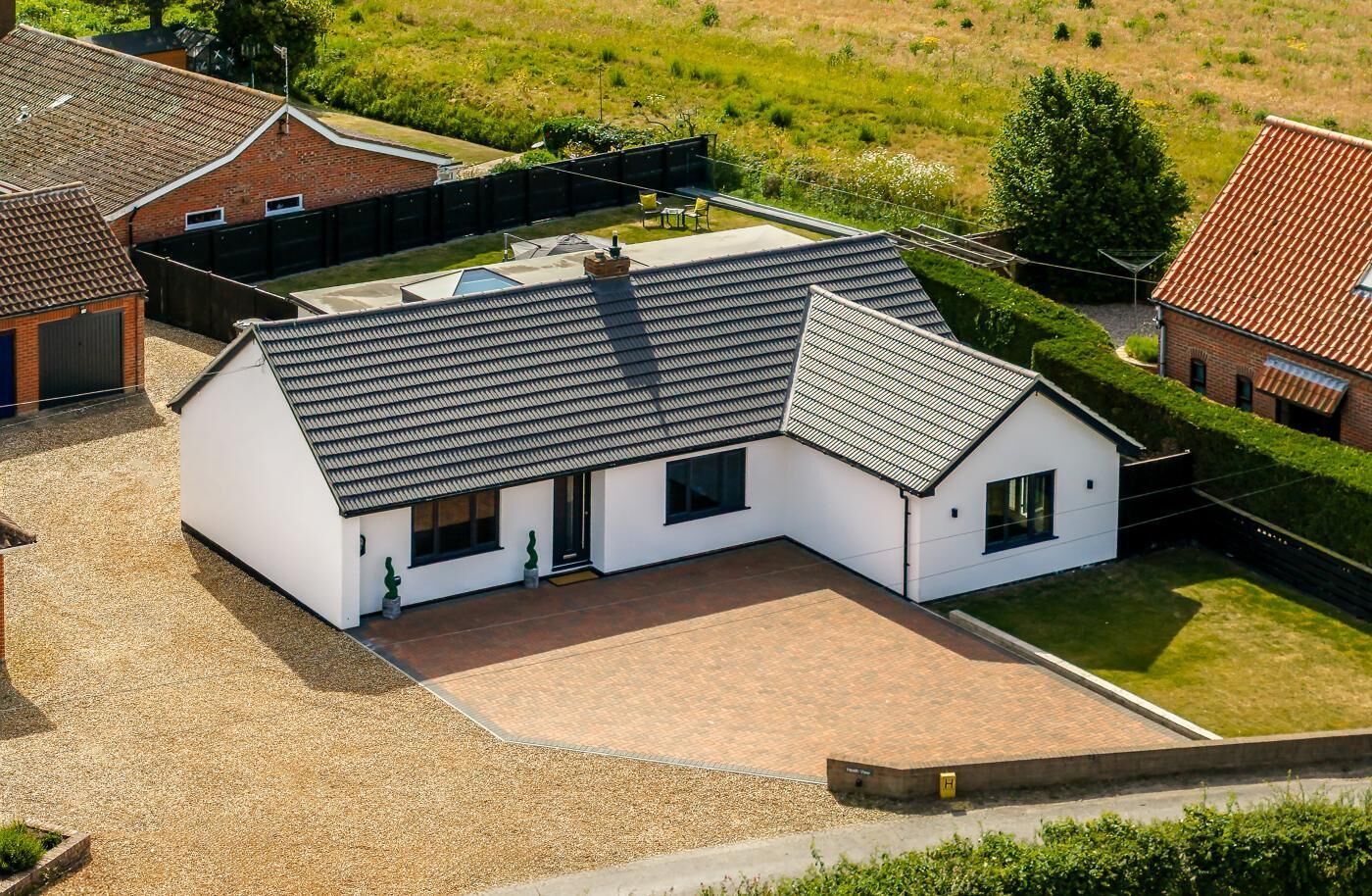A modern two-story house with a sloped roof, a covered patio, and a well-maintained lawn.