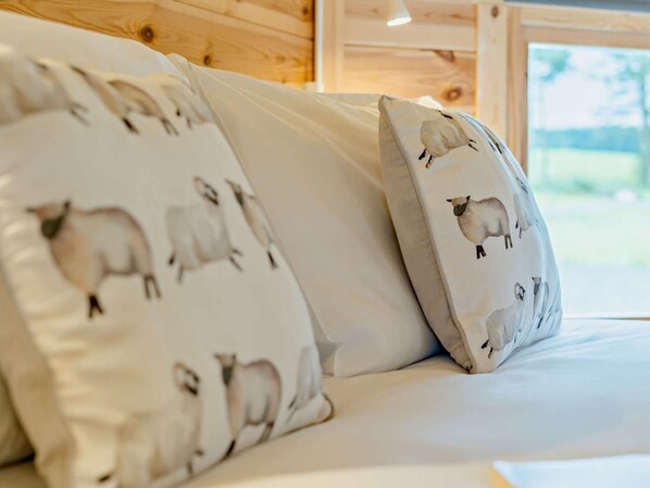 A bed with white bedding and pillows featuring sheep designs.