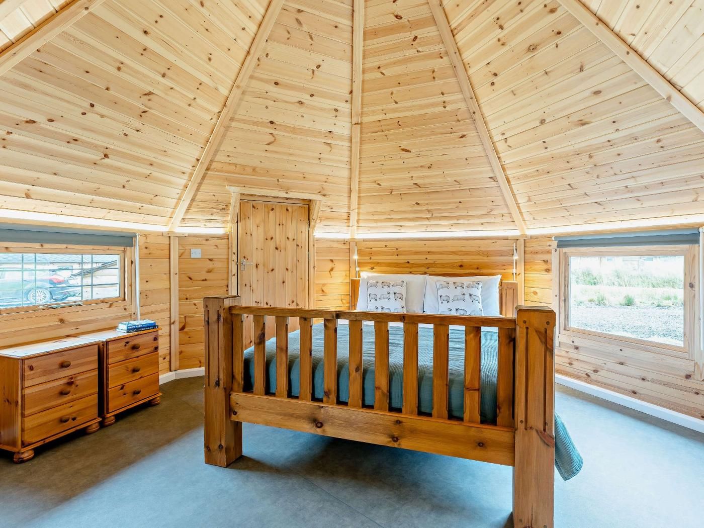Une chambre dans un chalet en bois, avec un lit superposé, une commode et des fenêtres offrant une vue.