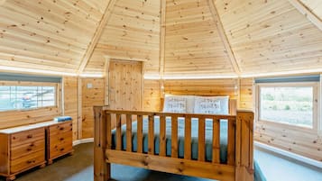 Une chambre dans un chalet en bois, avec un lit superposé, une commode et des fenêtres offrant une vue.