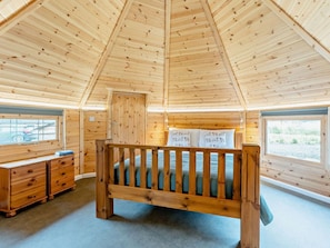 A wooden cabin room with a bunk bed, a dresser, and windows with views.