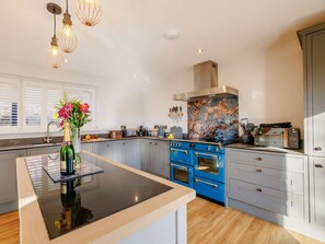 A modern kitchen with a central island, blue appliances, and a decorative backsplash. - 3 Bed in Dolgellau (oc-90805) (Llanelltyd)