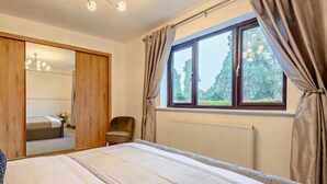 A bedroom with a bed, a chair, a wardrobe, and a window with curtains. - 3 Bed in Presteigne (oc-90768) (Kinnerton)
