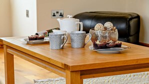 A wooden table with a white teapot, two patterned cups, and a decorative cup with a floral design. - 3 Bed in Presteigne (oc-90768) (Kinnerton)