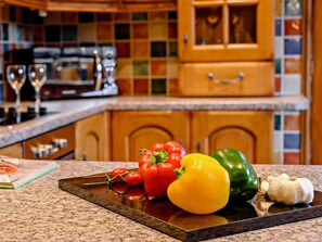 Un plan de travail de cuisine avec des légumes frais, un plateau et une bouteille.