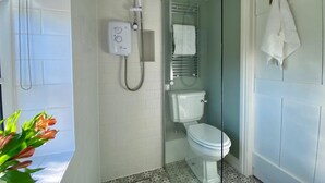 Een badkamer met douche, toilet en handdoekhouder.