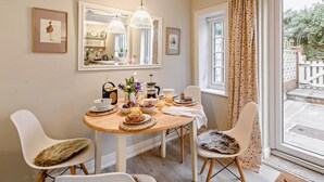 Een eetruimte met een ronde tafel, stoelen, een koffieapparaat en een ontbijt.