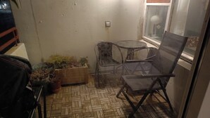 Pieni terassialue, jonka lattia on koristeltu kalanruotokuviolla, ja jossa on pyöreä pöytä, kaksi tuolia ja ruukkukasveja.
