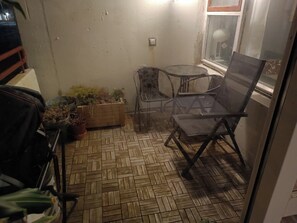 A small patio area with a herringbone-patterned floor, a round table, two chairs, and potted plants. - Charming 2-bedroom apartment in Seltjarnarnes (Seltjarnarnes)