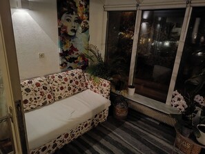 A room with a floral sofa, a large window with a view, a radiator, and a painting on the wall. - Charming 2-bedroom apartment in Seltjarnarnes (Seltjarnarnes)