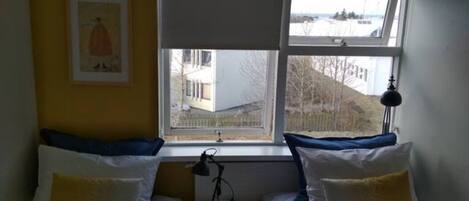 Une chambre avec deux lits, une fenêtre, une petite table et une lampe.