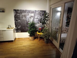A room with a cityscape view, wooden flooring, a small table with potted plants, and a sliding door. - Charming 2-bedroom apartment in Seltjarnarnes (Seltjarnarnes)
