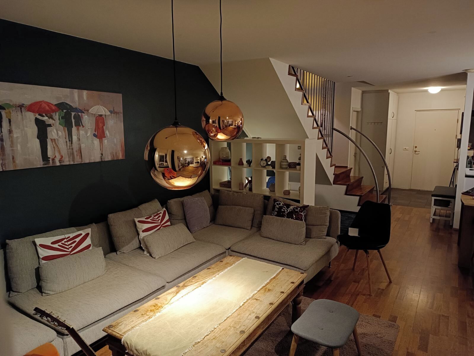 A living room with a sofa, a coffee table, a staircase, and a bookshelf.