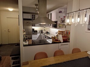 Una cocina moderna con una isla central, electrodomésticos de acero inoxidable e iluminación colgante.