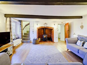 A living room with a fireplace, a sofa, a television, and a staircase. - 3 Bed in Holt (oc-90943) (Weybourne)
