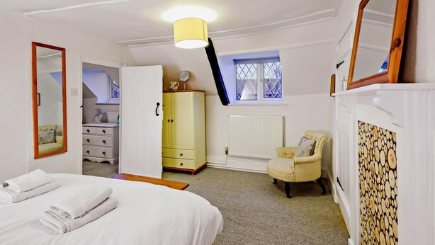 Een slaapkamer met een bed, een kledingkast, een stoel, een radiator en een raam met uitzicht.