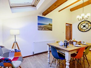 A dining area with a table, chairs, a lamp, a radiator, a clock, and a painting. - 3 Bed in Holt (oc-90943) (Weybourne)