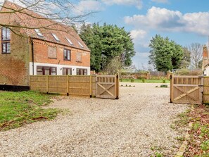 A gravel driveway leading to a brick house with a wooden gate. - 2 Bed in Norwich (oc-90882) (Limpenhoe)
