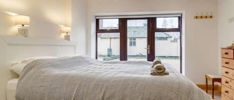 A bedroom with a bed, bedside lamps, a window, and a wooden dresser.