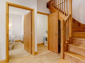 A multi-level wooden staircase with a handrail, leading to a bedroom with a bed and a washing machine. - 2 Bed in Norwich (oc-90882) (Limpenhoe)