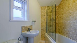 Une salle de bain avec un lavabo, des toilettes, une douche et une fenêtre.