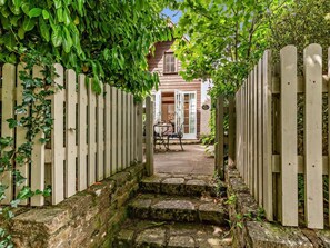 A stone pathway leading to a wooden gate with a house in the background. - 1 Bed in Minehead (oc-90923) (Minehead)