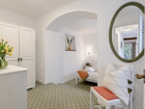 A room with a checkered floor, a white bench, a bed with an orange throw, and a mirror with a green frame. - 1 Bed in Minehead (oc-90923) (Minehead)