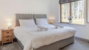 A bedroom with a bed, bedside tables, a window with a view of trees, and a lamp. - 2 Bed in King's Lynn (oc-91275) (North Runcton)
