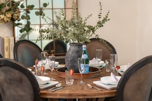 A dining table set with plates, cutlery, and glasses, a bottle of water, and a vase with greenery. - Near Gondola & Lake | Private Hot Tub| Free Ski Shuttle & Parking (Whistler)